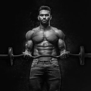 Black and white portrait of a muscular man lifting weights, showcasing strength and fitness.